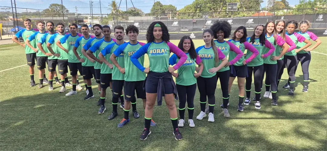 Equipe BORA! reunida no campo com os uniformes verdes, azuis e rosas